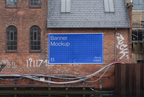 Outdoor banner mockup on a brick building with graffiti backdrop. Ideal for designers showcasing large-format graphics templates. Urban setting, realistic preview.