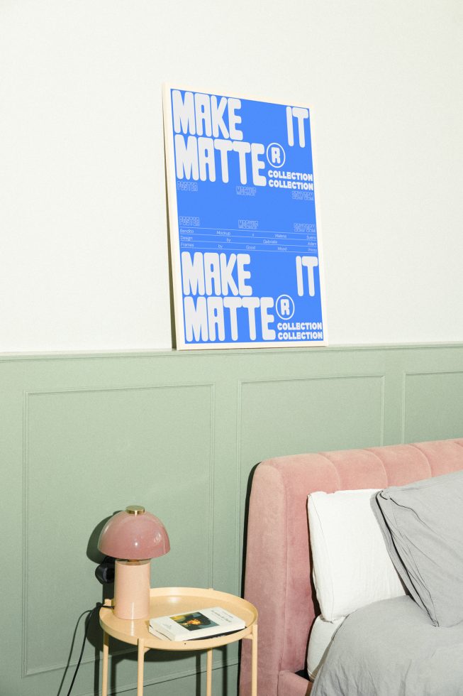 Mockup poster on a light green wall above a pink velvet bed and beige nightstand with a lamp and books, ideal for designers showcasing graphics.