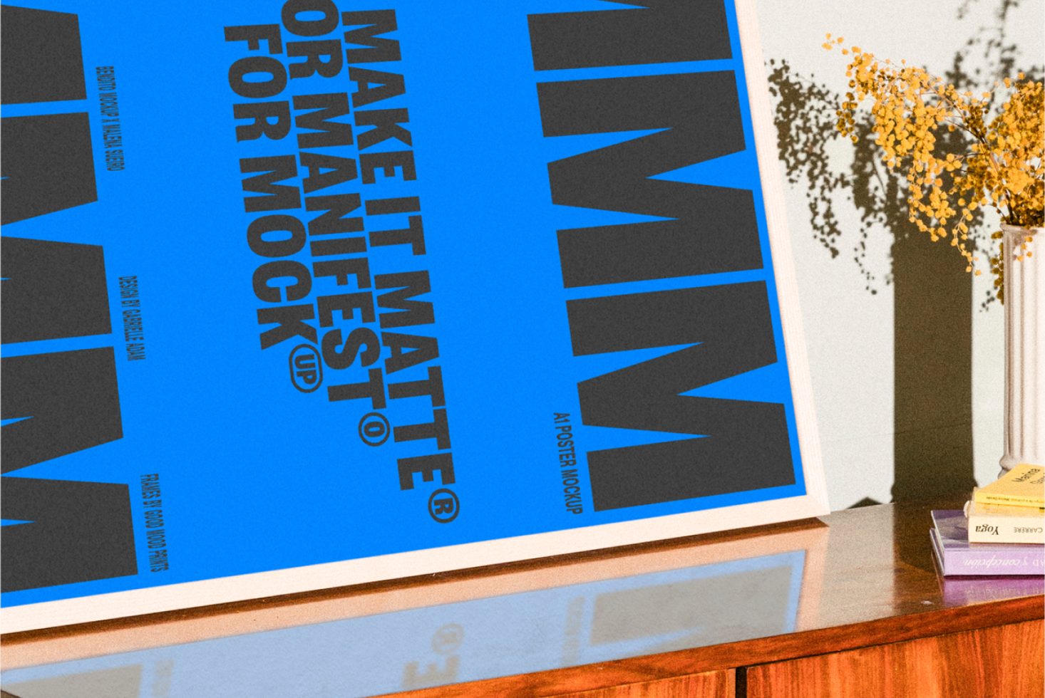 Poster mockup design featuring bold black text on blue background propped on a wooden table with decorative flowers; ideal for designers Posters Templates