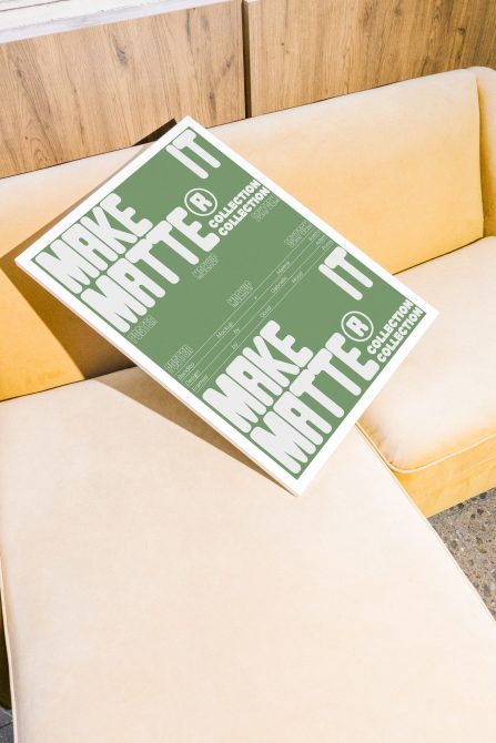 Matte poster mockup with bold typography on a green background, placed on a beige couch; mockup, poster, design asset, graphic template, for designers