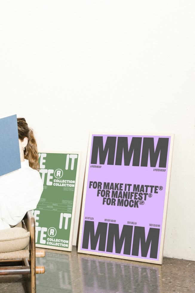 Designer reading blue book on chair beside green and purple poster mockups for digital assets suitable for designers and showcasing matte and manifest themes.