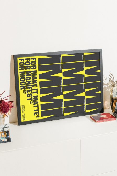 Modern framed poster mockup on a white table, featuring bold yellow and black typography design, ideal for showcasing graphic templates for digital assets.