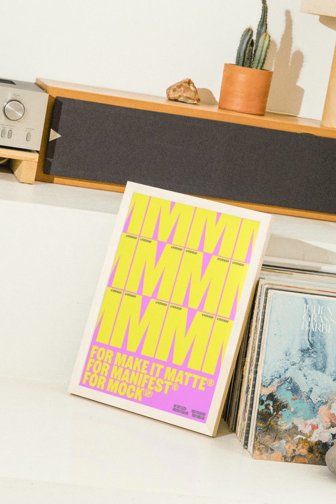 Poster mockup on a wooden shelf beside vinyl records and decor items. Bright colors for modern design. Perfect for designers looking for vibrant mockup templates.