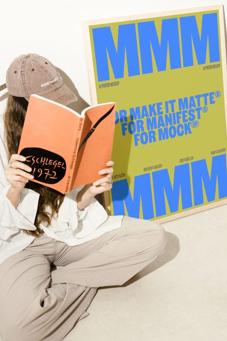 Person reading book with large A1 poster mockup behind; ideal for graphic designers creating posters, templates, or mockups in digital asset marketplaces.