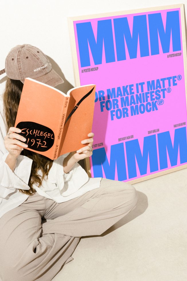 Person reading a book with a framed colorful poster mockup in the background. Ideal for designers seeking premium poster mockups for their projects.