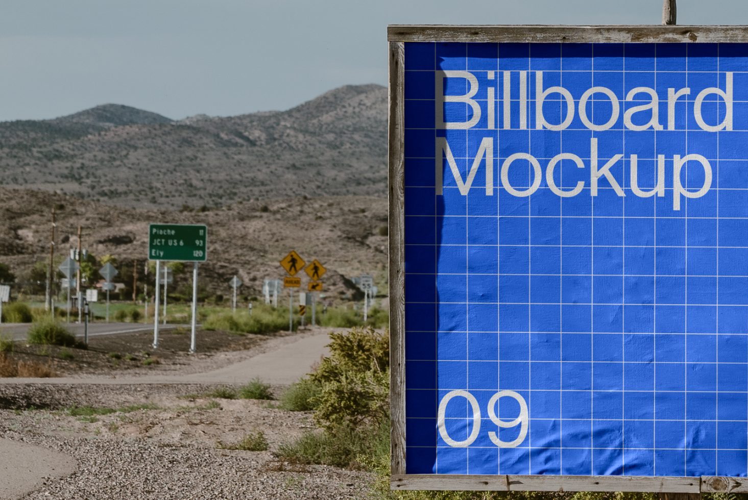 Billboard mockup in a desert landscape with road signs and mountain backdrop. Perfect for designers needing outdoor advertising mockups for marketing projects.