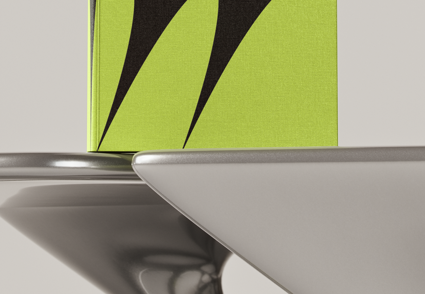 Close-up of a modern book cover mockup showcasing black abstract art on a lime green background standing on a sleek metallic surface.