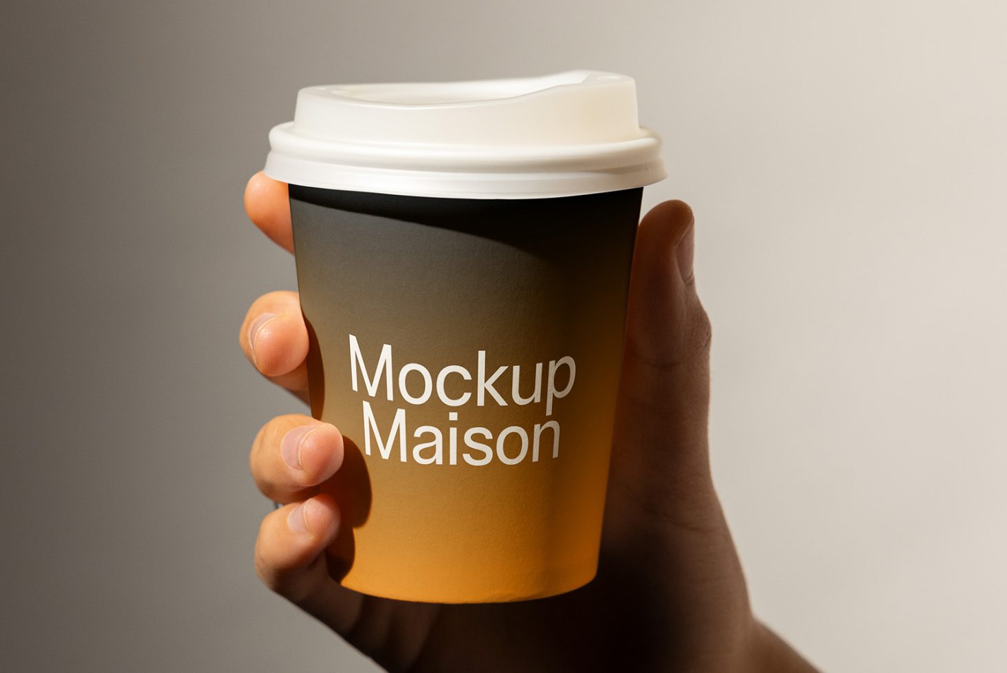 Hand holding a takeaway coffee cup mockup with logo text Mockup Maison for showcasing branding designs. Perfect for designers looking for realistic mockups.