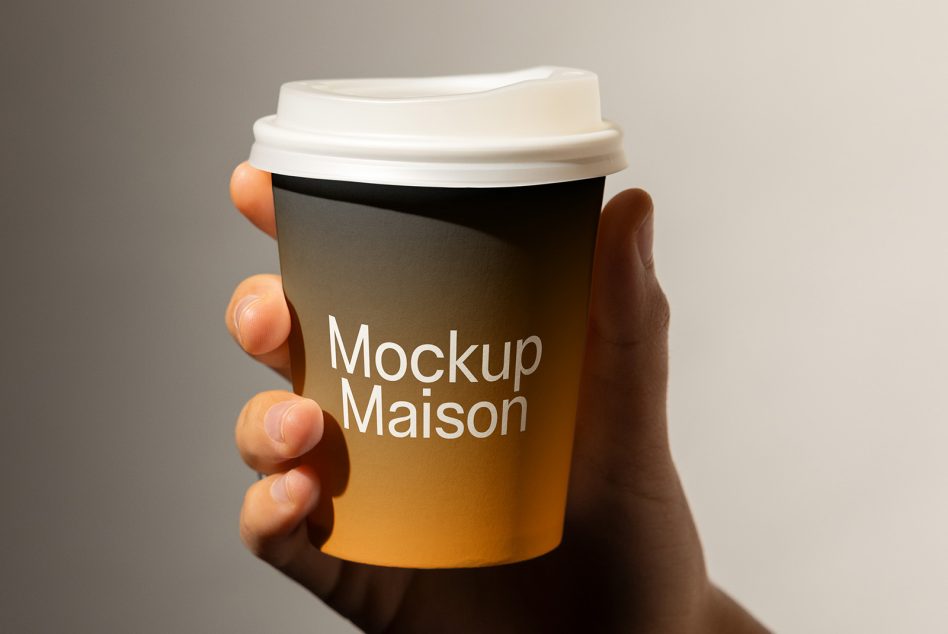 Hand holding gradient coffee cup mockup with white lid on neutral background