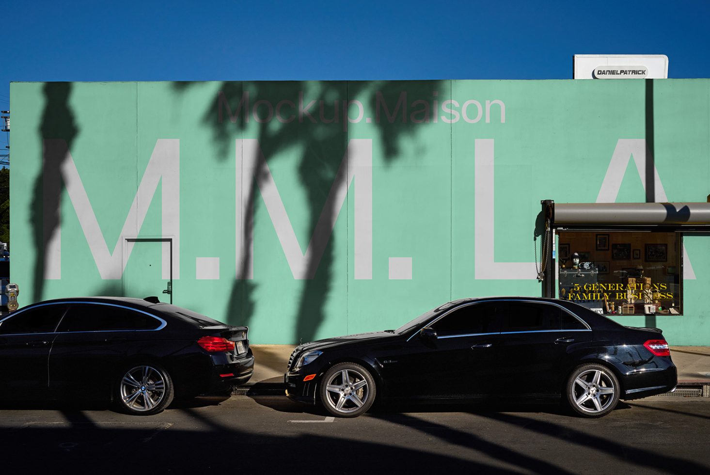 Outdoor wall signage mockup with large text MMLA showing shadows of palm trees. Ideal for designers creating realistic mockups and urban graphic designs.