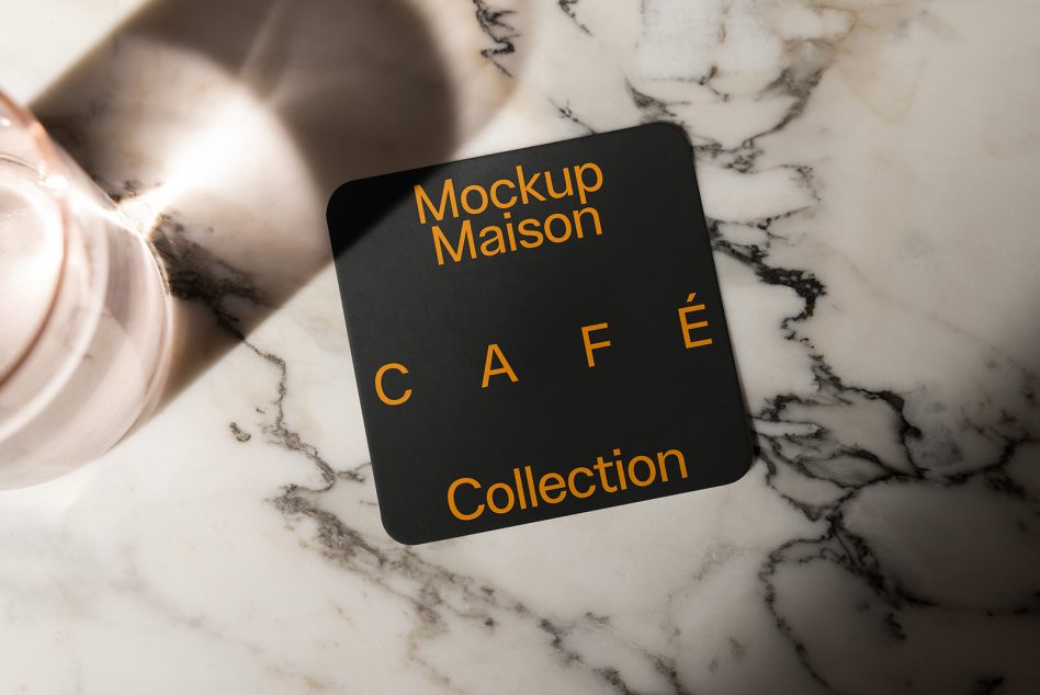 Orange gold text coaster on black rounded square, marble background, coffee cup visible