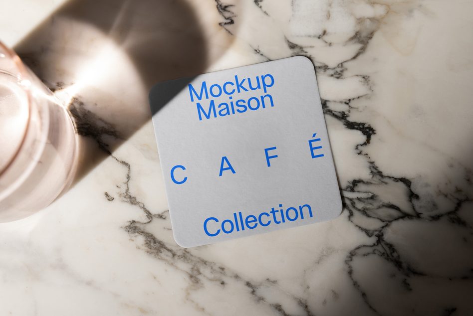 Blue text coaster on marble surface next to white ceramic cup, minimal flat lay