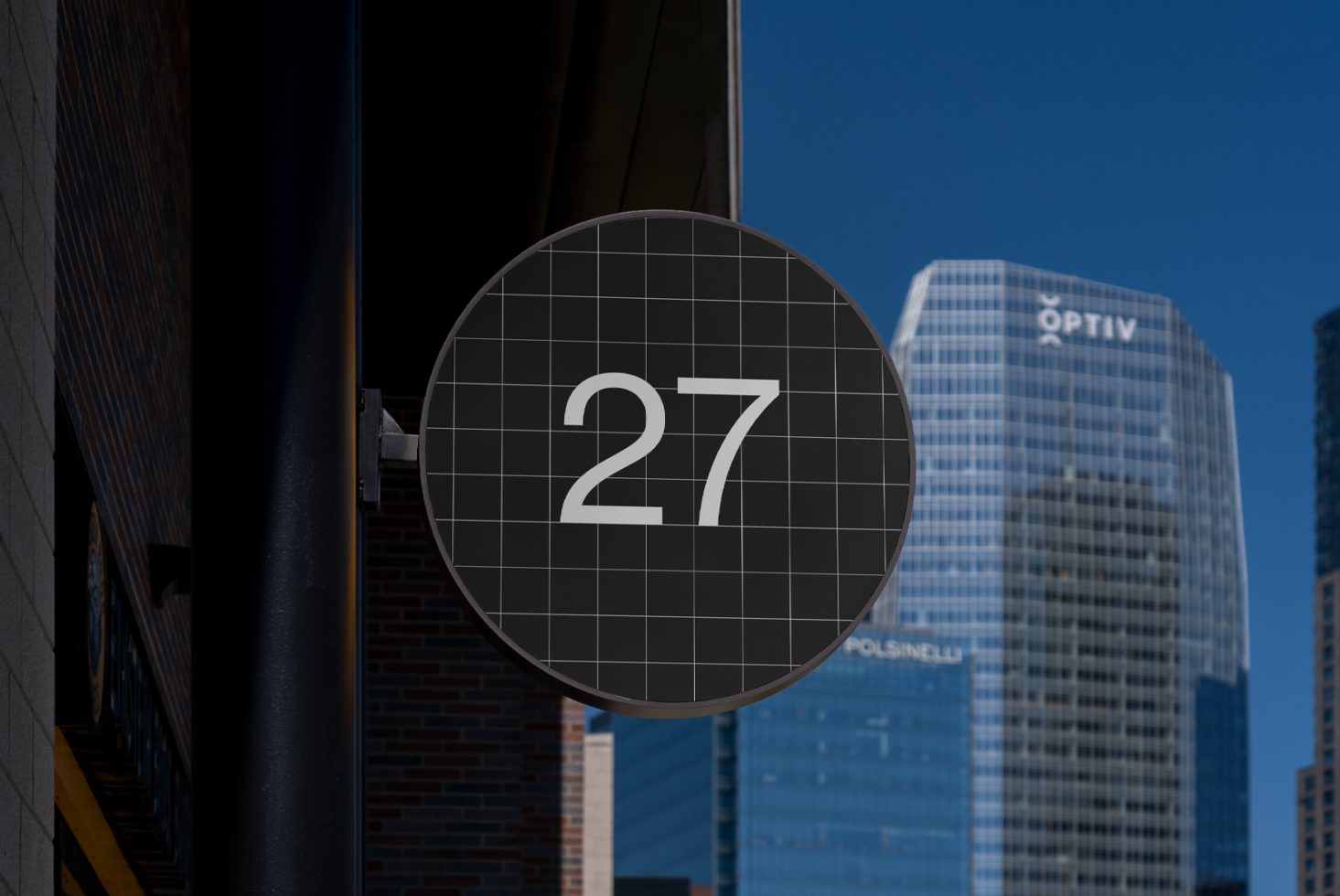 Circular metal sign with number 27 in front of glass skyscraper mockup template for digital assets urban design modern architecture-background designers