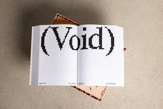 Open A4 book mockup displaying the word Void in large pixelated font placed on a textured surface suitable for mockup designs and digital assets.