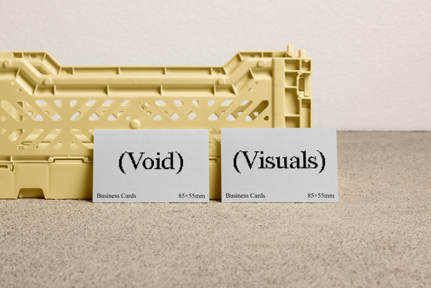 Business card mockup showcasing two minimalist cards with text Void and Visuals, placed in front of a yellow crate on a textured surface, suitable for designers.