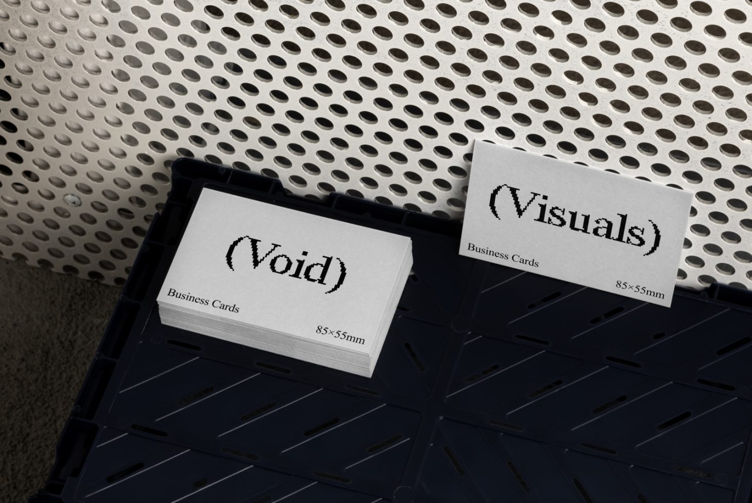 Mockup of business cards in grayscale with pixelated font placed on a textured surface in a dark plastic tray suitable for designers on Marketplace.