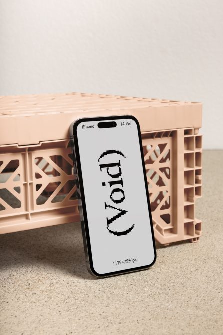 Black iPhone 14 Pro on beige plastic crate showing pixelated text display