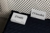 Business cards spread on dark tray showing pixelated branding on white stock