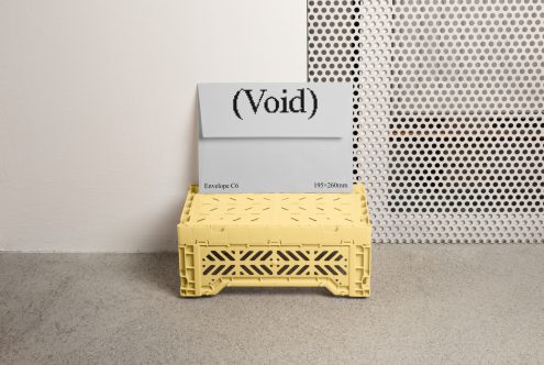 Envelope C6 mockup with text Void 195x260mm printed, placed on a yellow plastic crate. Ideal for designers for presentation on digital asset marketplaces.