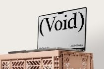 MacBook Pro mockup tilted with pixelated void text on screen over tan crate