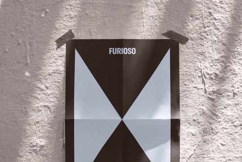 Folded geometric poster with bold black and white triangles taped to textured wall suitable for graphic design mockups posters and templates background