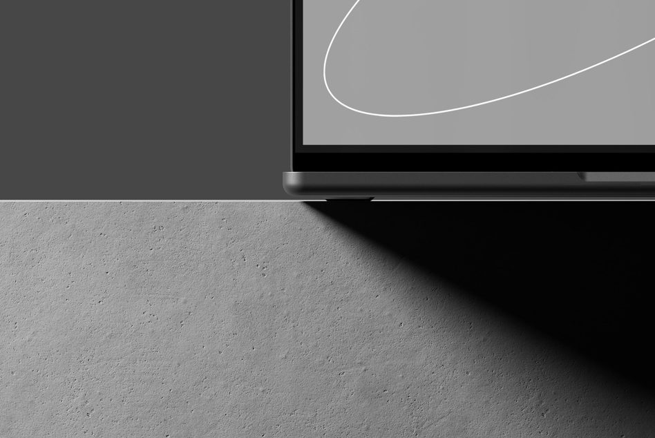 Minimalist laptop mockup showing corner detail on concrete surface with shadows for designers in mockups and templates category suitable for digital assets.