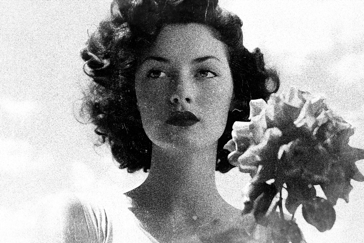 Vintage black-and-white photo of a woman with curly hair and a large flower. Perfect for designers needing retro textures, art, photography, and stylish templates.