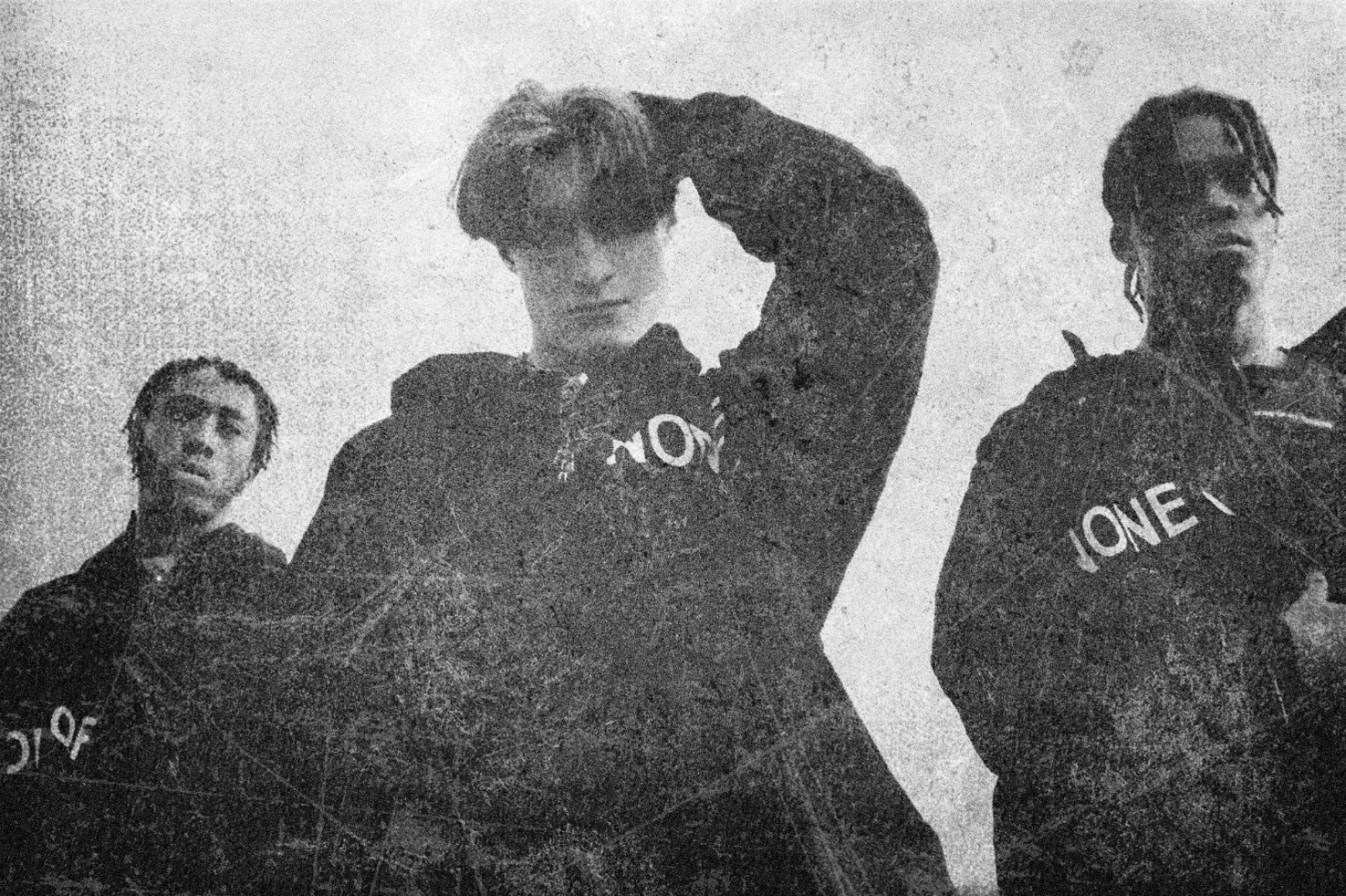 Grunge black and white photo showing three young men in hoodies under a cloudy sky. Perfect for digital design, graphic projects, vintage effects, textures.