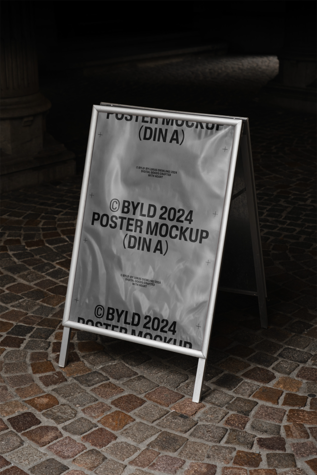 Outdoor poster mockup template with a metal frame and cobblestone background perfect for showcasing design work. Mockup categories: Graphics, Templates, Mockups.