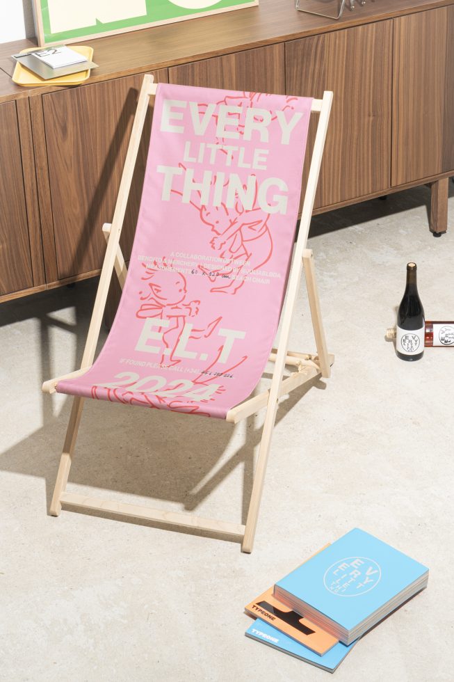 Mockup of pink beach chair featuring bold text Every Little Thing beside wine bottles and books. Ideal for showcasing graphic designs. Perfect for designers.