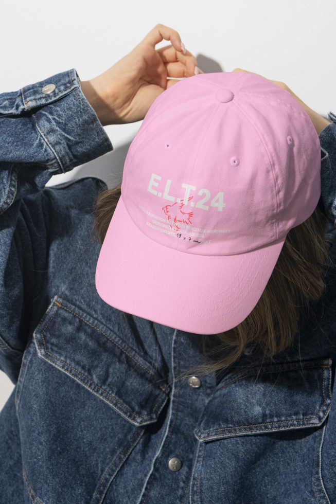 Designer wearing denim jacket adjusting pink cap with text E.L.T24 suitable for mockups templates promotional graphics fashion branding assets