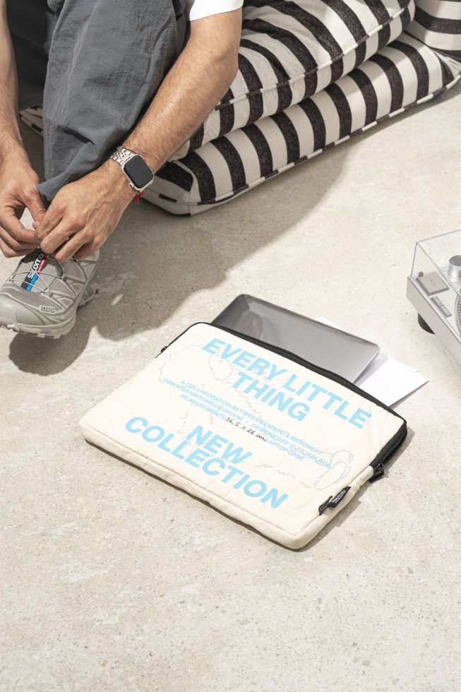 Laptop sleeve mockup on the ground next to person tying shoe with striped cushion. Perfect for designers looking for mockups and templates for new collection displays.