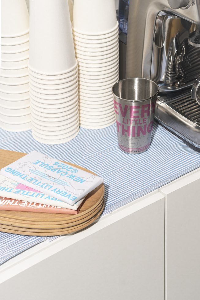 Photo of a kitchen counter with stacked disposable cups, a stainless steel cup, an espresso machine, a cloth, and a wooden tray. Perfect for mockups, graphics.