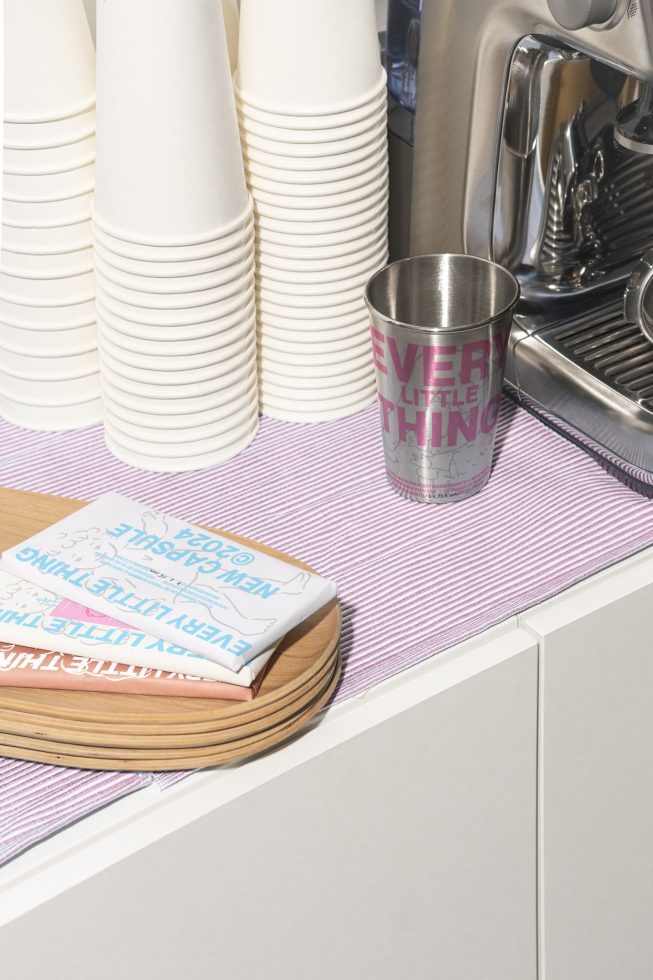 Coffee station showcasing a stack of disposable cups, metal mug, napkins on wooden trays near an espresso machine. Perfect for cafe mockups, templates, or graphics.