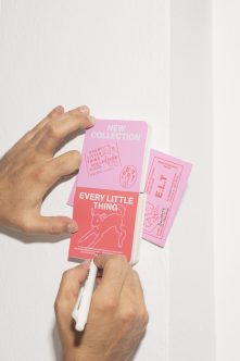 Hands holding pink, white, plus light pink book mockups from flat lay