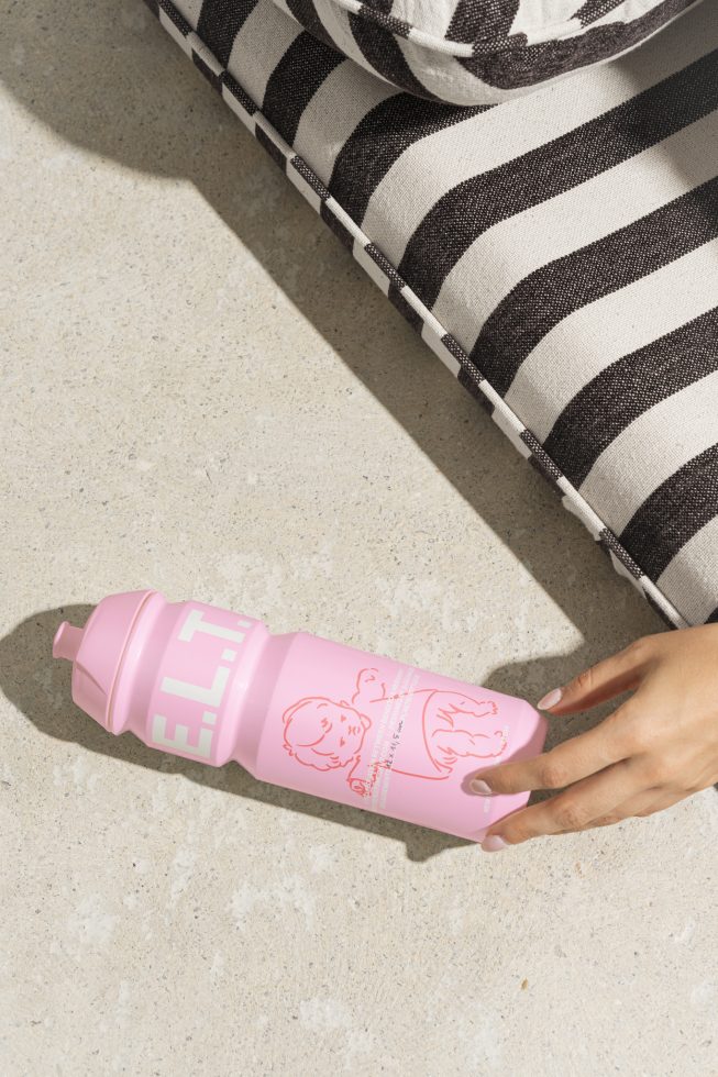 Designer mockup showing a hand reaching for a pink plastic water bottle with childlike illustrations and text. Label design, packaging template for graphics.