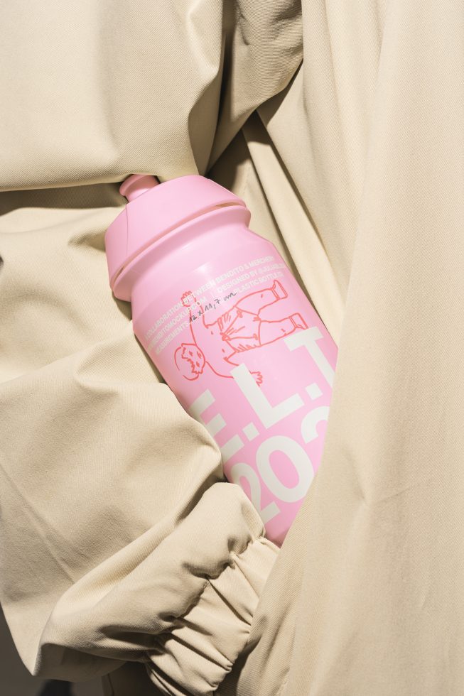 Pink water bottle with graphic design on beige fabric template for designers customizable PSD mockup modern graphics for packaging and branding projects