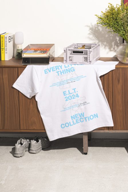 T-shirt mockup 2024 collection draped over cabinet. Near sneakers, books, and plant. Perfect for showcasing graphic design and t-shirt templates for designers.