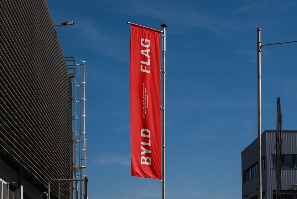 Outdoor flag mockup with red banner displaying BYLD FLAG text on a modern building background perfect for graphic designers and marketing templates