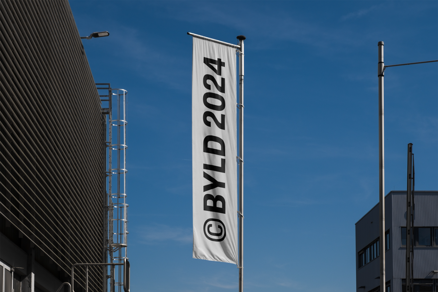 Modern building exterior showcasing a tall flagpole with a vertical 2024 BYLD banner perfect for urban location mockups and outdoor advertising templates.