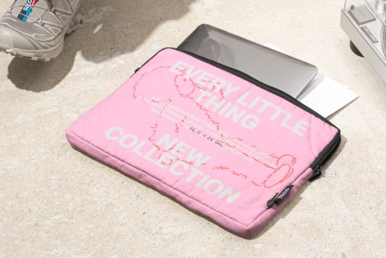 Pink laptop sleeve with text Every Little Thing New Collection placed on a concrete surface with a laptop partially inside. Ideal for graphic designers.