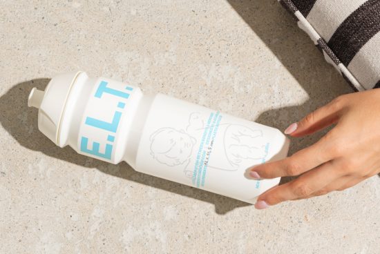 Close-up view of a white water bottle on textured surface next to a hand and striped pillow ideal for mockup templates product design branding advertisements