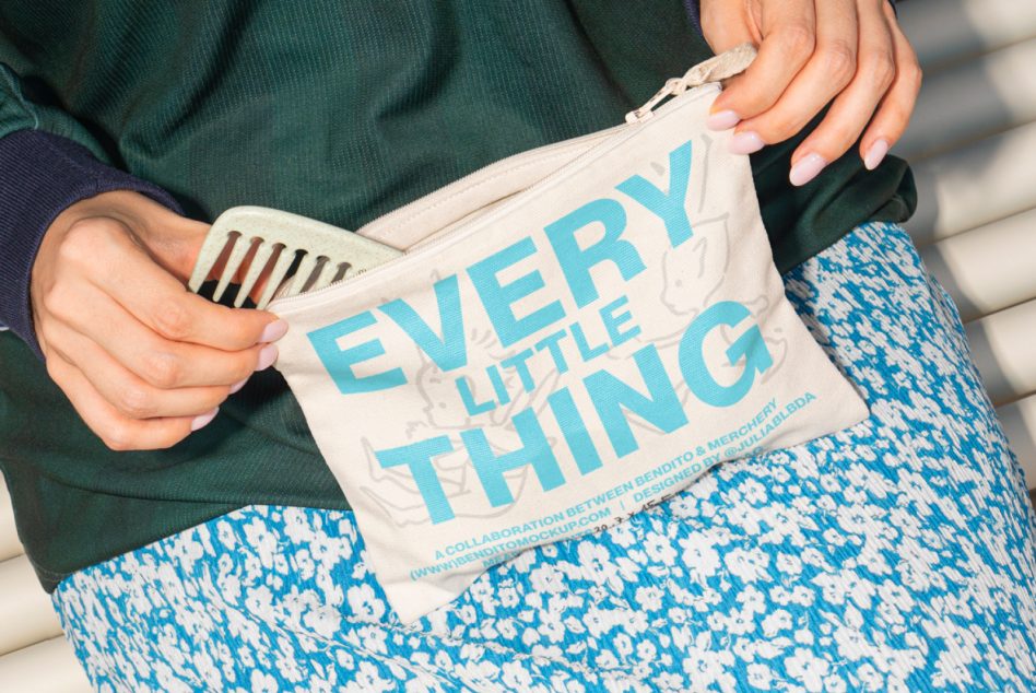 Person holding cream tote bag with blue typography, blue geometric print pants