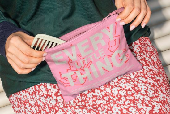 Close-up of a person holding a pink pouch with the text Every Little Thing. Ideal for mockups, templates. Keywords: mockups, templates, pouches, pink, design assets.