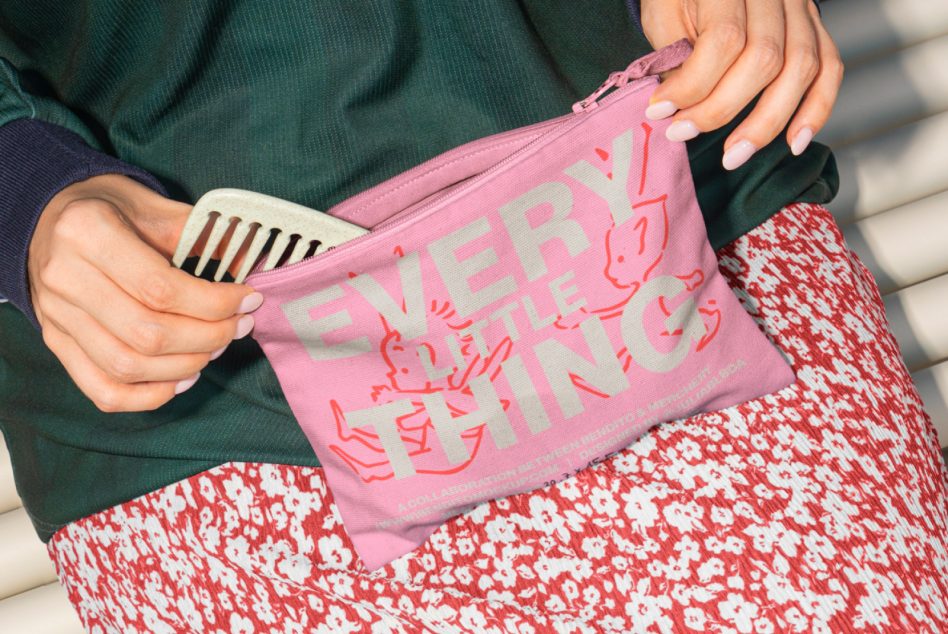 Close up of pink zippered pouch with large text, red floral skirt in frame