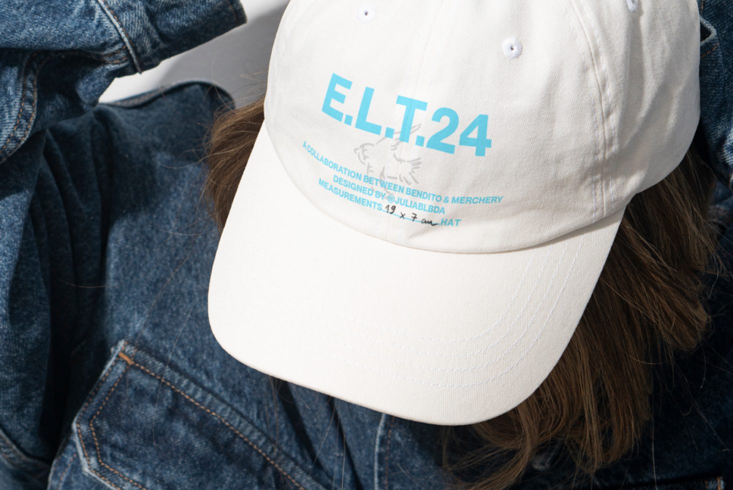 White cap with blue text E.L.T.24 designed for collaboration. SEO keywords: cap mockup design, white hat graphic, font template, product showcase.