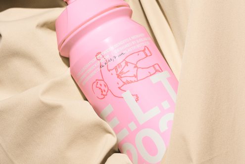 Pink plastic bottle with minimalist design lying on beige fabric. Ideal for packaging mockups, product design projects, and branding presentations