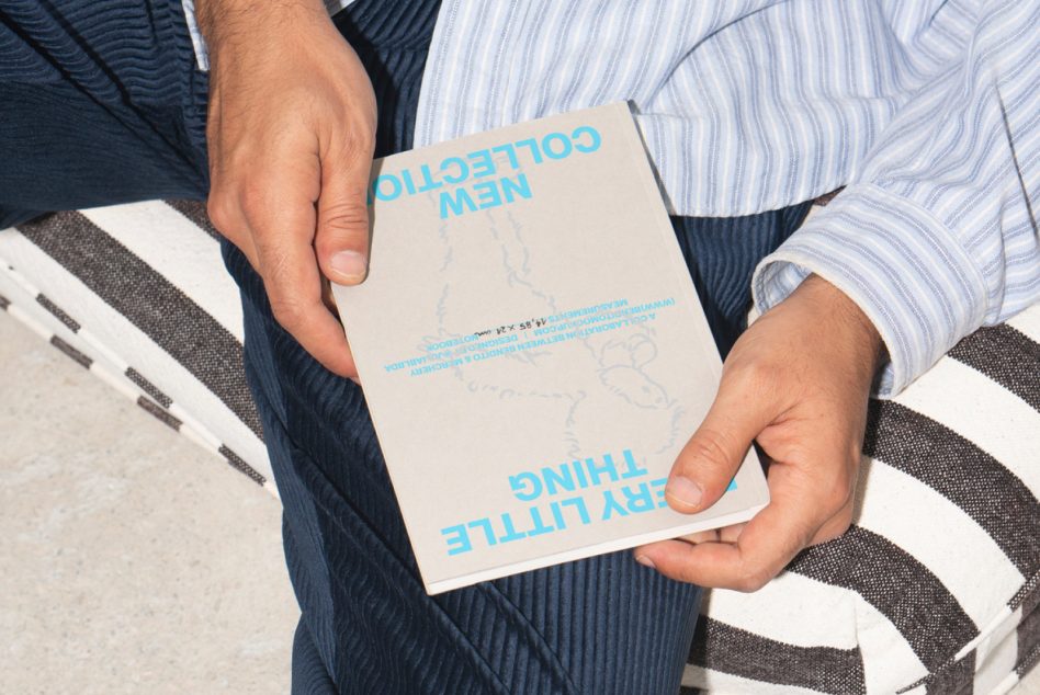 Man holding a minimalist design mockup book in beige cover with blue text. Ideal for designers seeking inspiration and fresh ideas for their projects.