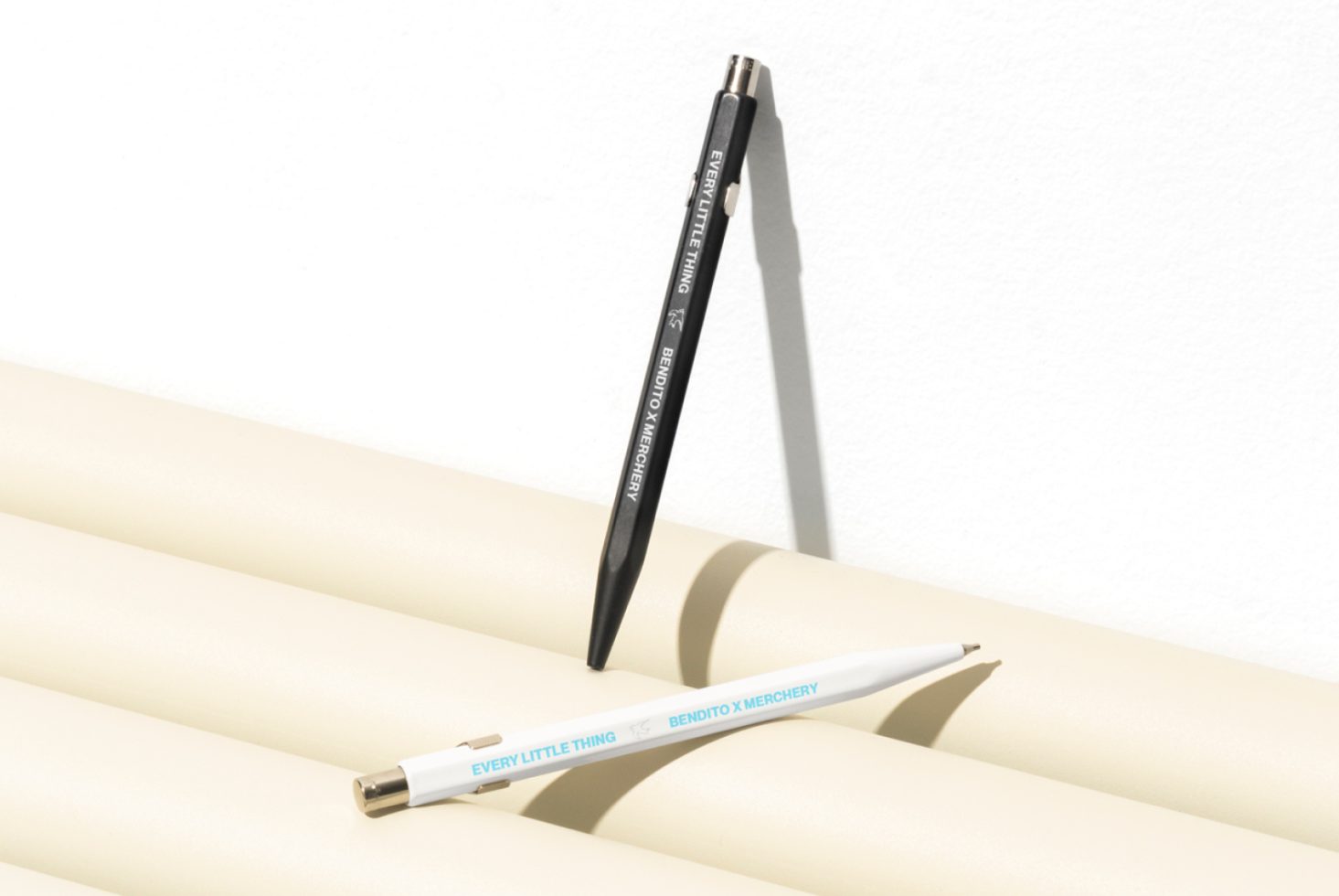 Two stylish pens, one black and one white, on a minimal beige background, perfect for stationery mockups or graphic design templates, enhancing office branding.