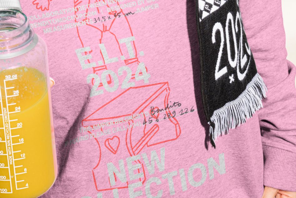 Close-up mockup of a pink sweatshirt with E.L.T. 2024 design and text print; person holding a juice bottle wearing a scarf. Perfect for graphics and templates.